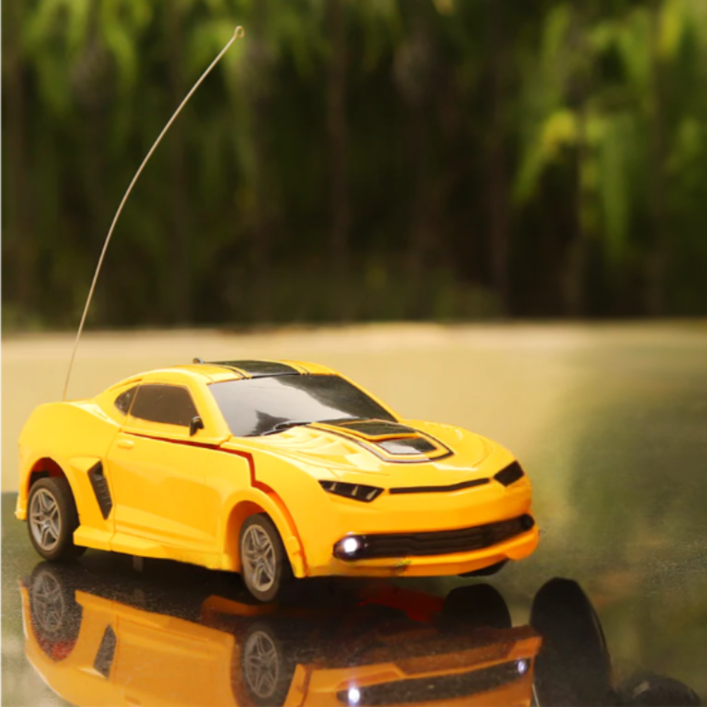 Yellow remote control sports car toy with LED headlights on a reflective surface outdoors.